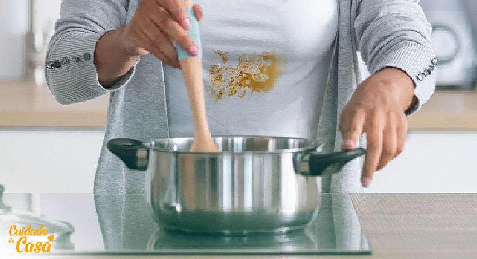 Mulher cozinhando com a roupa manchada e querendo saber como tirar mancha de óleo da roupa