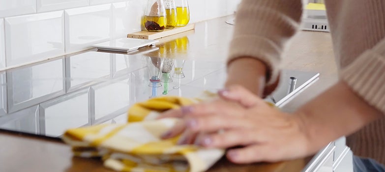 Persona limpiando la mesa con un paño impregnado de vinagre 