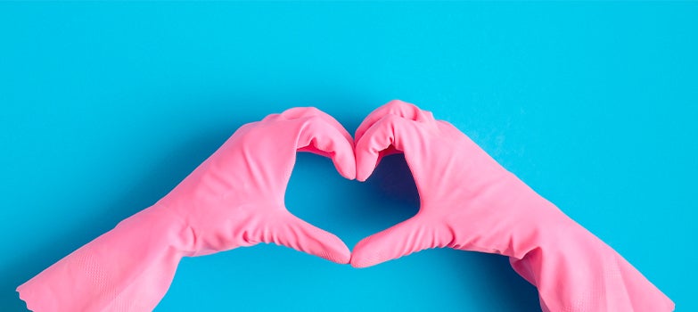 Manos con guantes rosados formando un corazón con los dedos