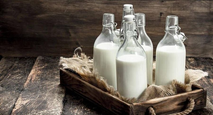 Leche casera pasteurizada en frascos de vidrio sobre una mesa rústica