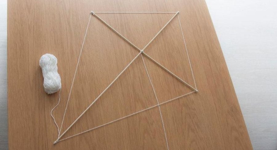 Palos de madera en equis e hilo grueso formando la silueta del papalote