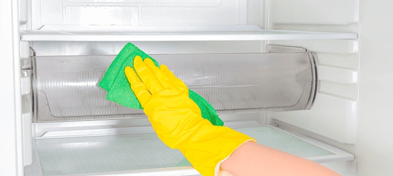 Mujer abriendo un refrigerador impecable, con alimentos saludables organizados.