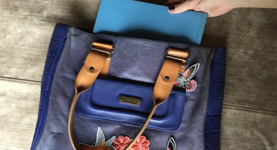 mano-poniendo-cuaderno-azul-dentro-de-bolso.jpg metiendo cuaderno