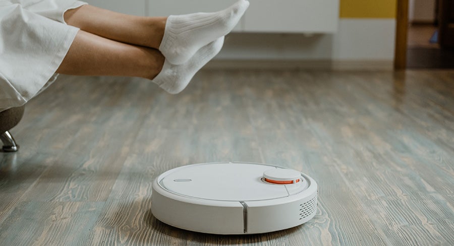 aspiradora inteligente limpiando mientras persona se relaja en el sofá