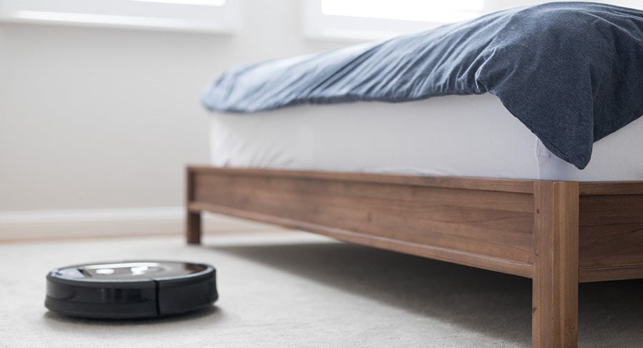 aspiradora robot limpiando el piso junto a la cama